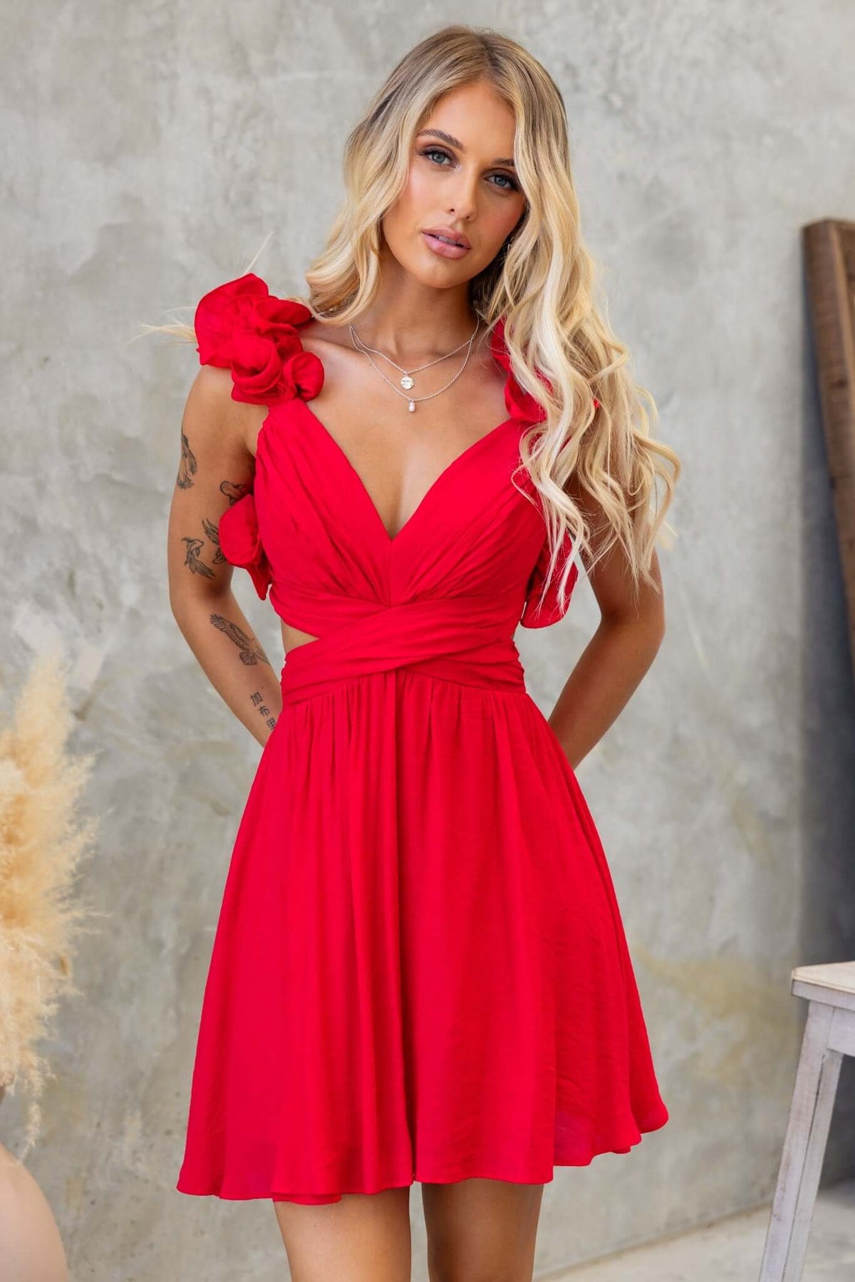 Luciana Dress in red featuring a V-neckline, ruffle strap detail, and a flattering cut-out waist design.