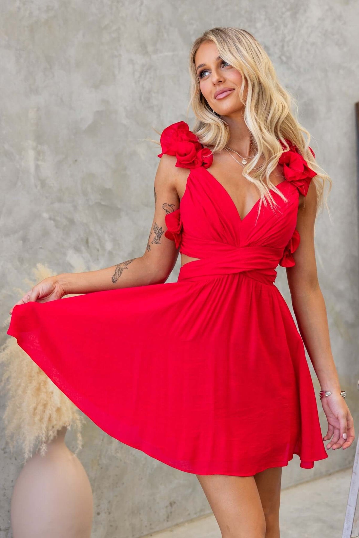 Model wearing a red Luciana Dress with a V-neckline, ruffle straps, and a cut-out waist.