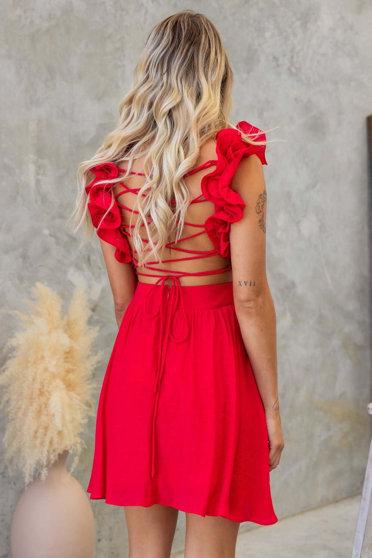 Back view of Luciana Dress featuring red ruffle straps, lace-up tie, and cut-out waist design, perfect for summer outings.