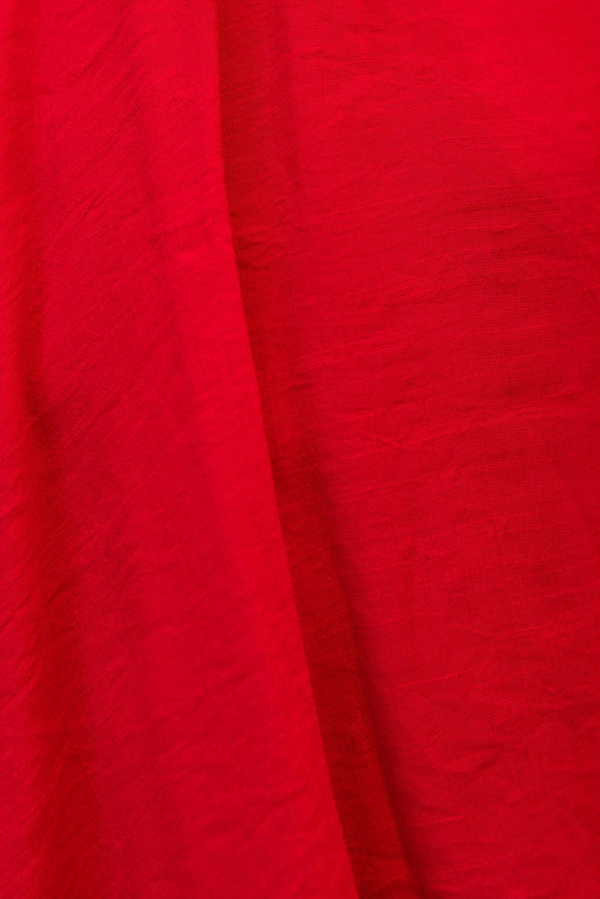 Close-up of vibrant red chiffon fabric, showcasing its texture and color, perfect for elegant dress designs.