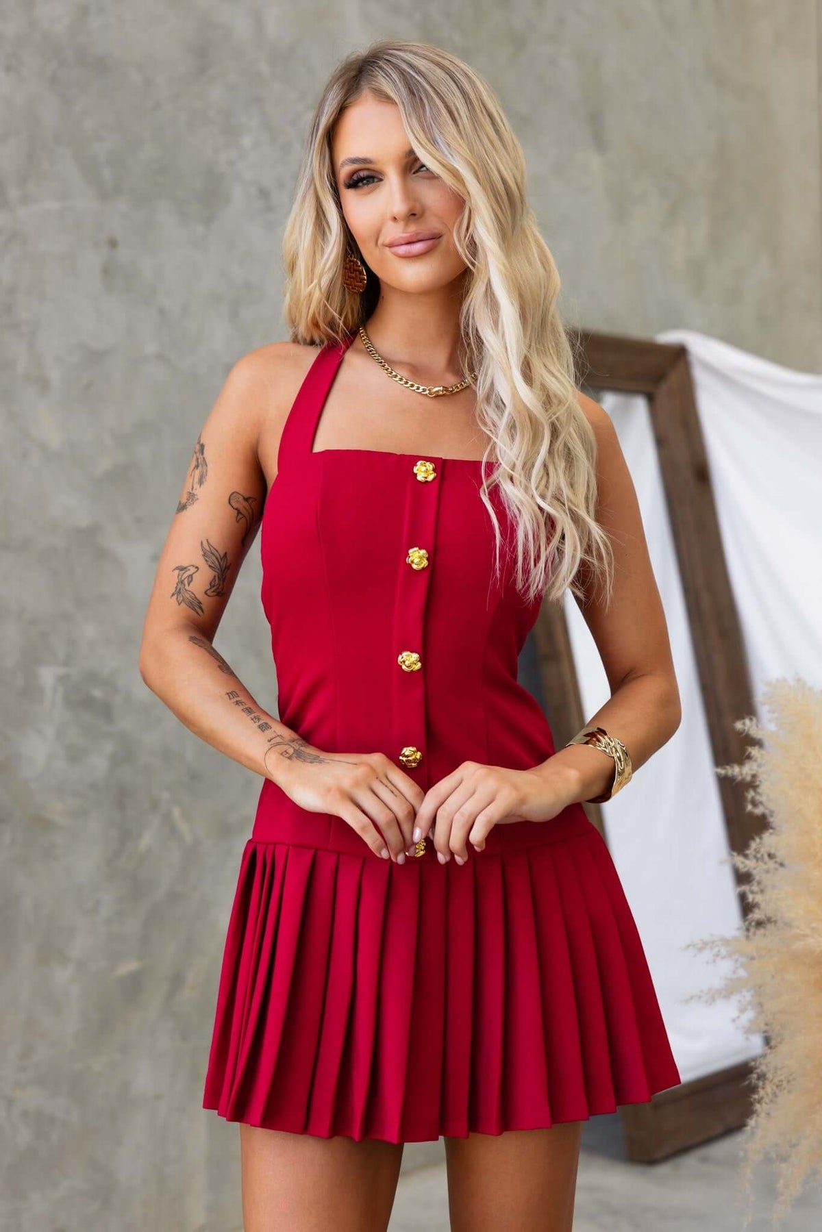 Red Cosabella dress with tie straps, faux buttons, and a pleated skirt, styled and worn by a model.