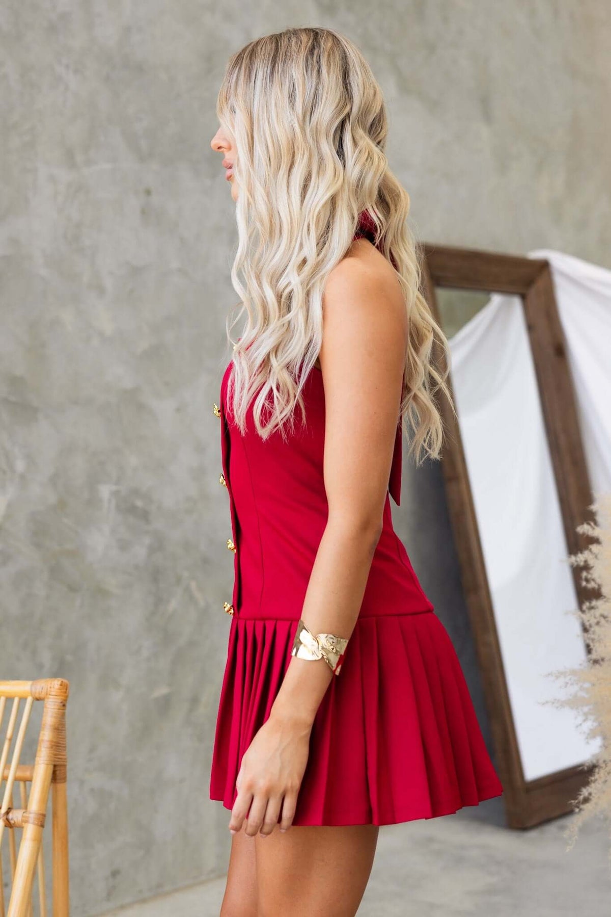 Side view of a woman in a red Cosabella dress with tie straps and pleated skirt.