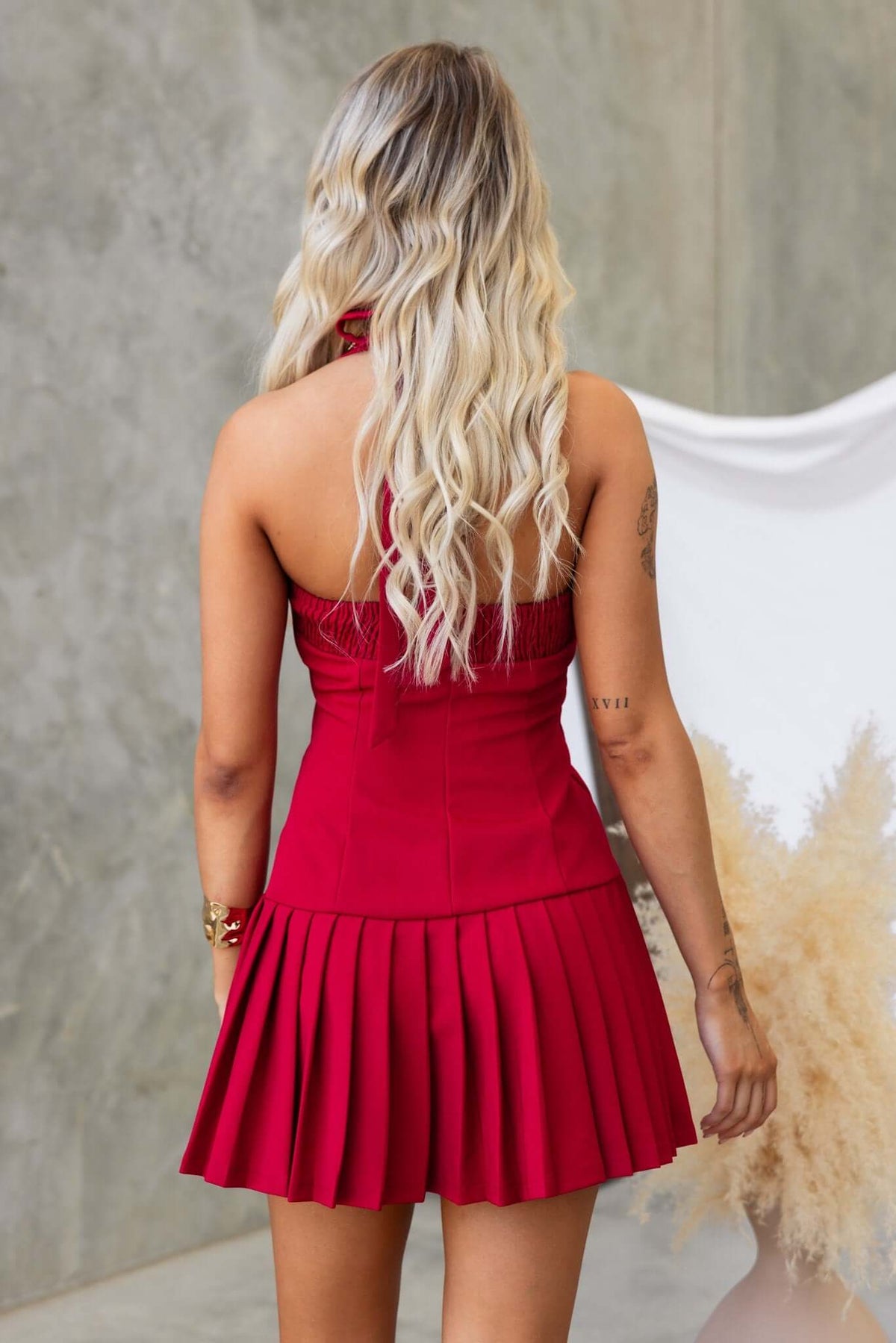 Back view of a model wearing a red Cosabella dress with tie straps and pleated skirt.