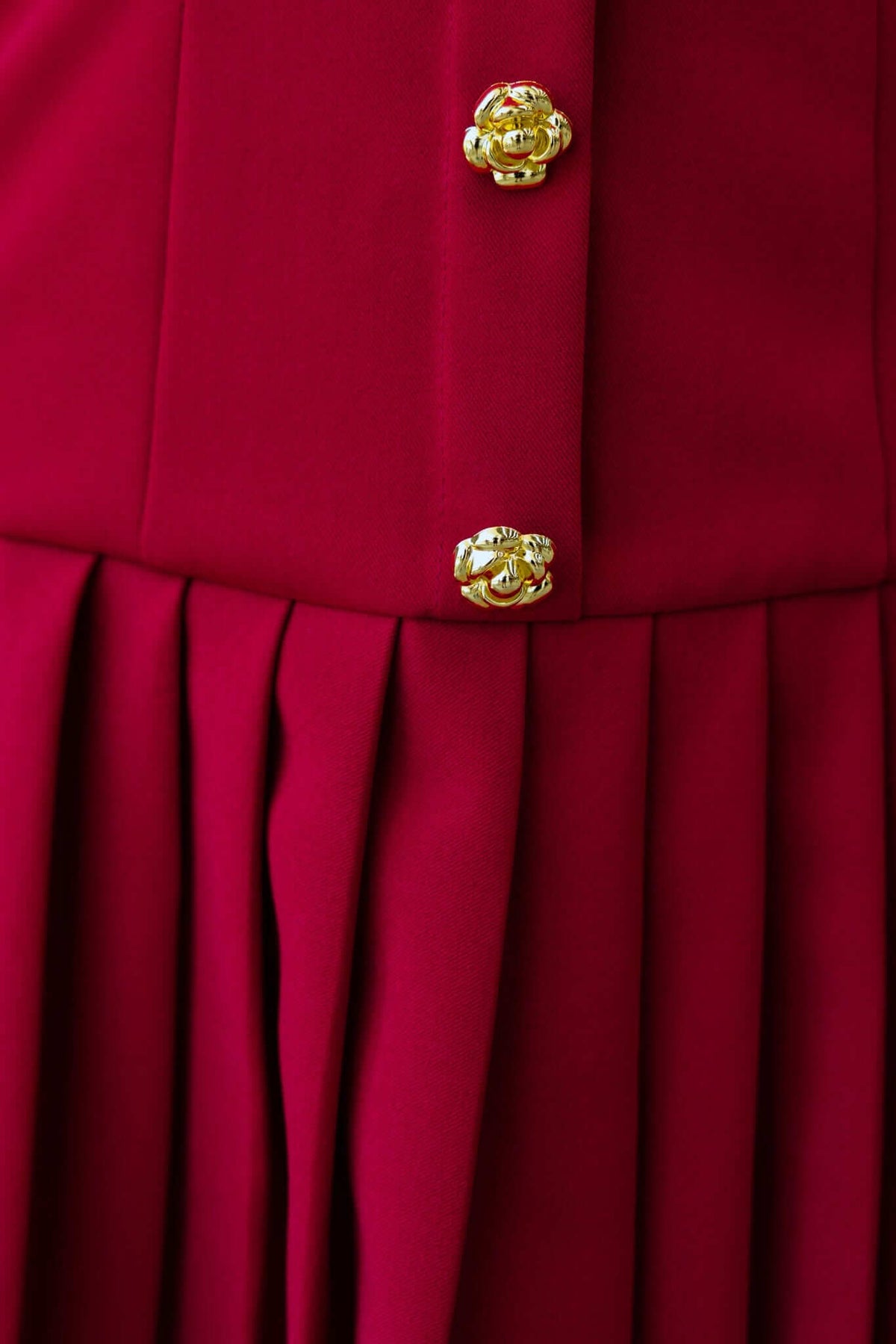 Close-up of the Cosabella dress featuring faux buttons and pleated fabric in deep red.