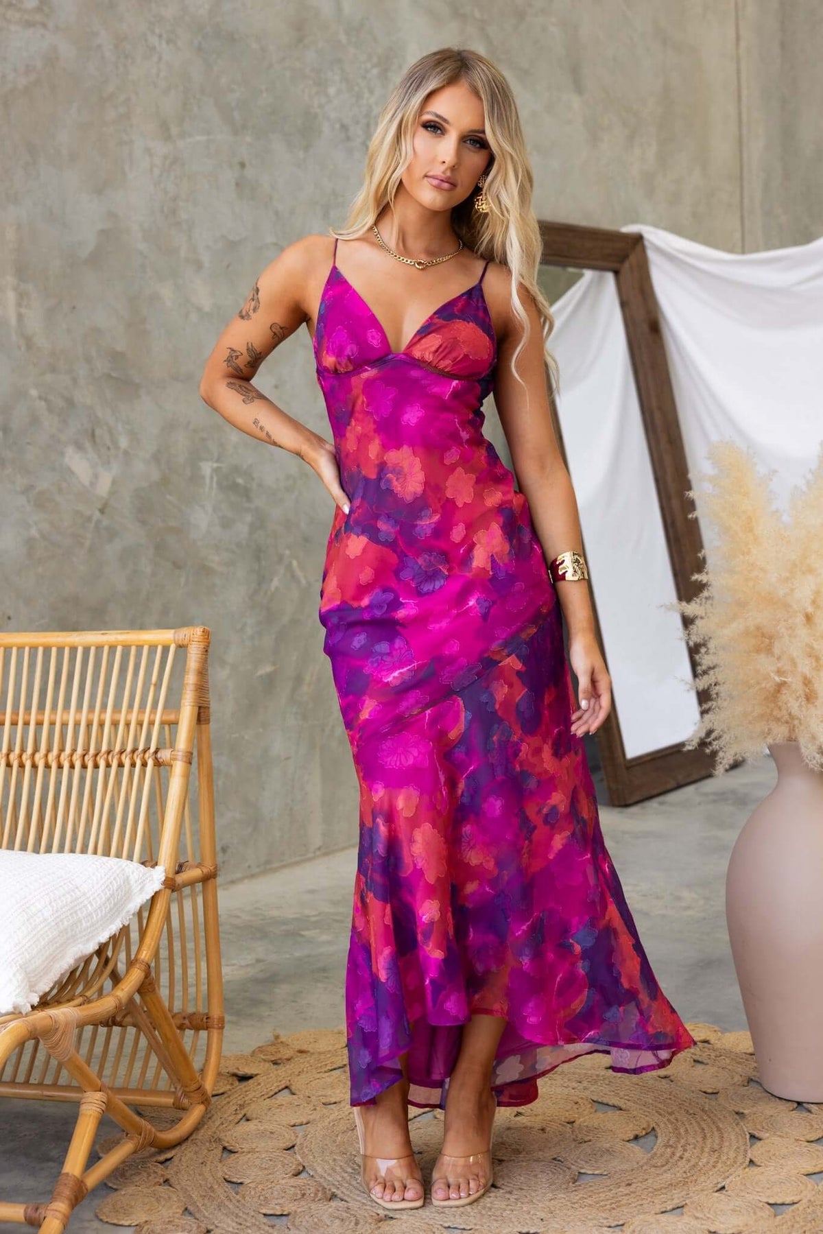 Model wearing Fontana Maxi Dress with adjustable straps and high-low hem in vibrant pink and purple floral pattern.