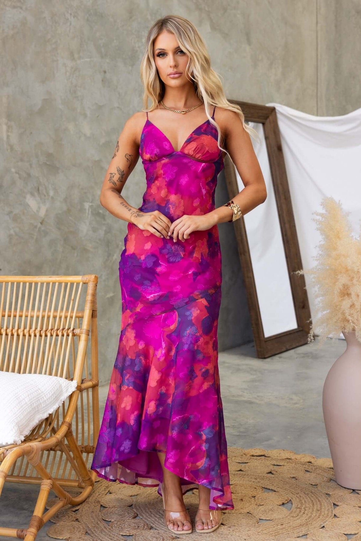 Model in a purple floral Fontana Maxi Dress with adjustable straps and a high-low hem, styled in a chic setting.