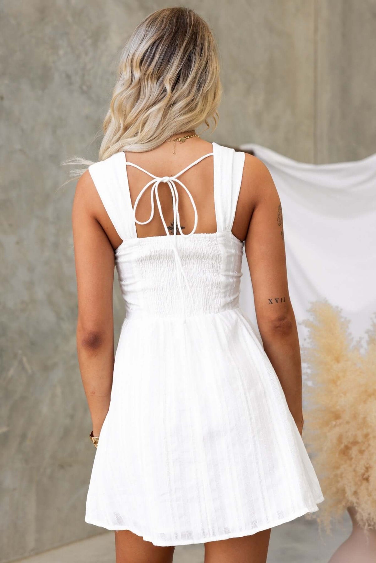 Back view of the Haizel Dress featuring tie details and elastic neckline, in a chic white design with a lightweight cotton feel.