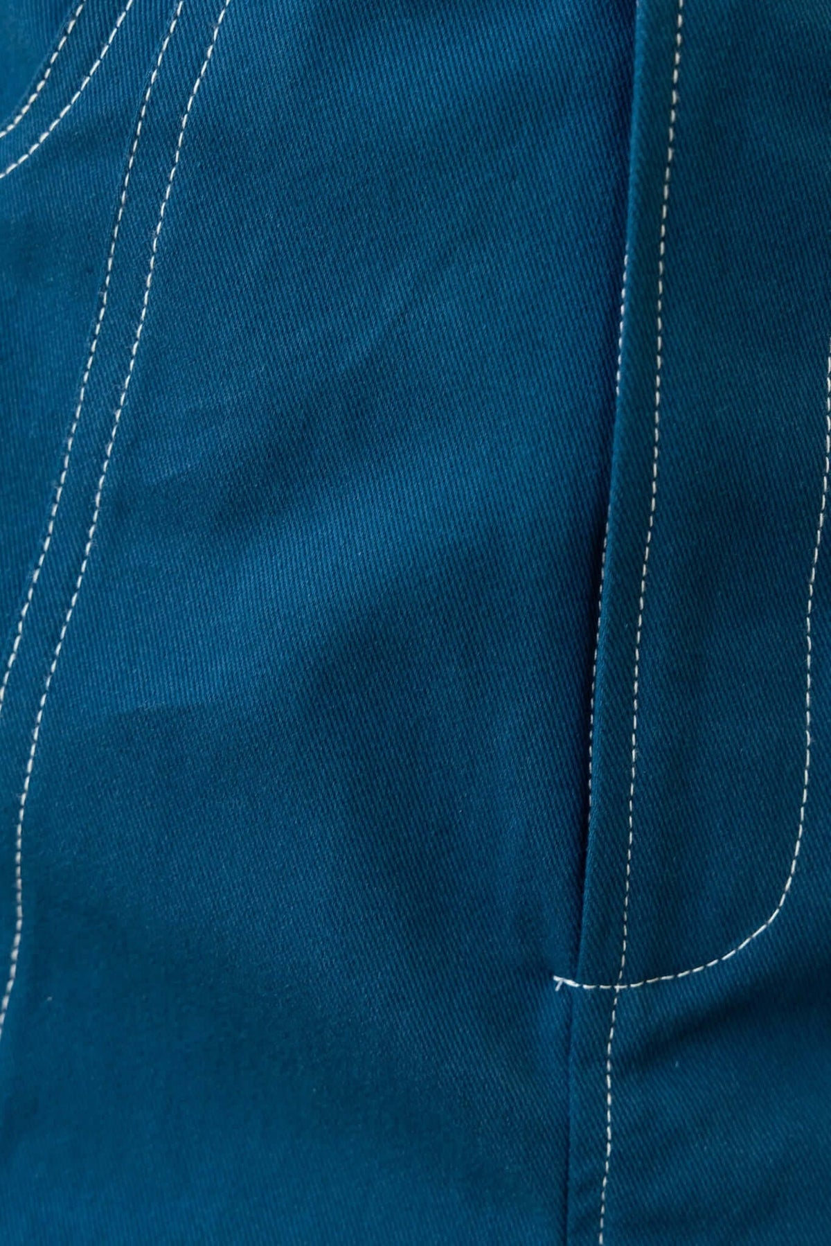 Close-up of Salone Denim Playsuit showing rich blue fabric and white stitching detail.