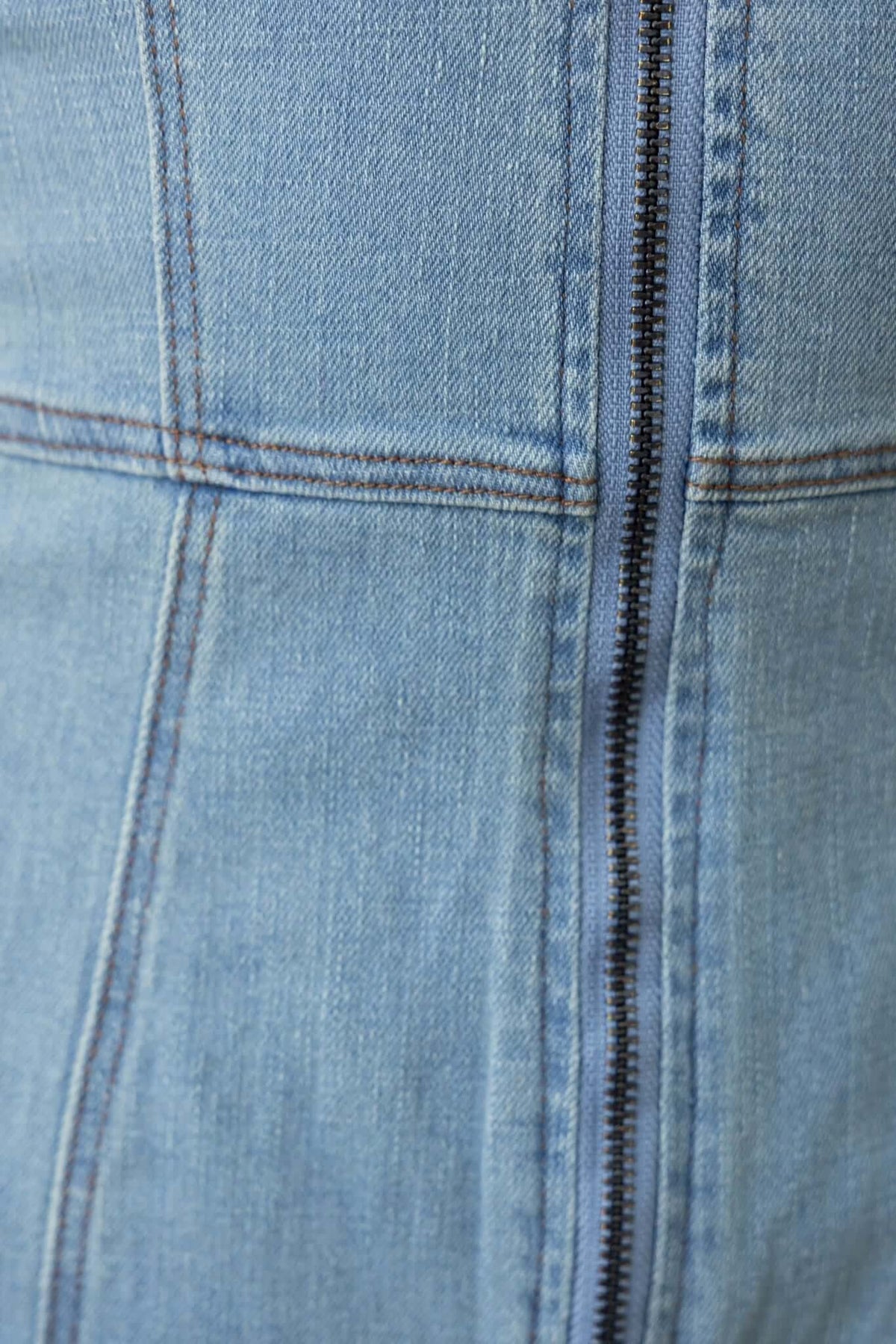 Close-up of the zip-up front of a Qarter denim playsuit with stretch material and blue denim finish.