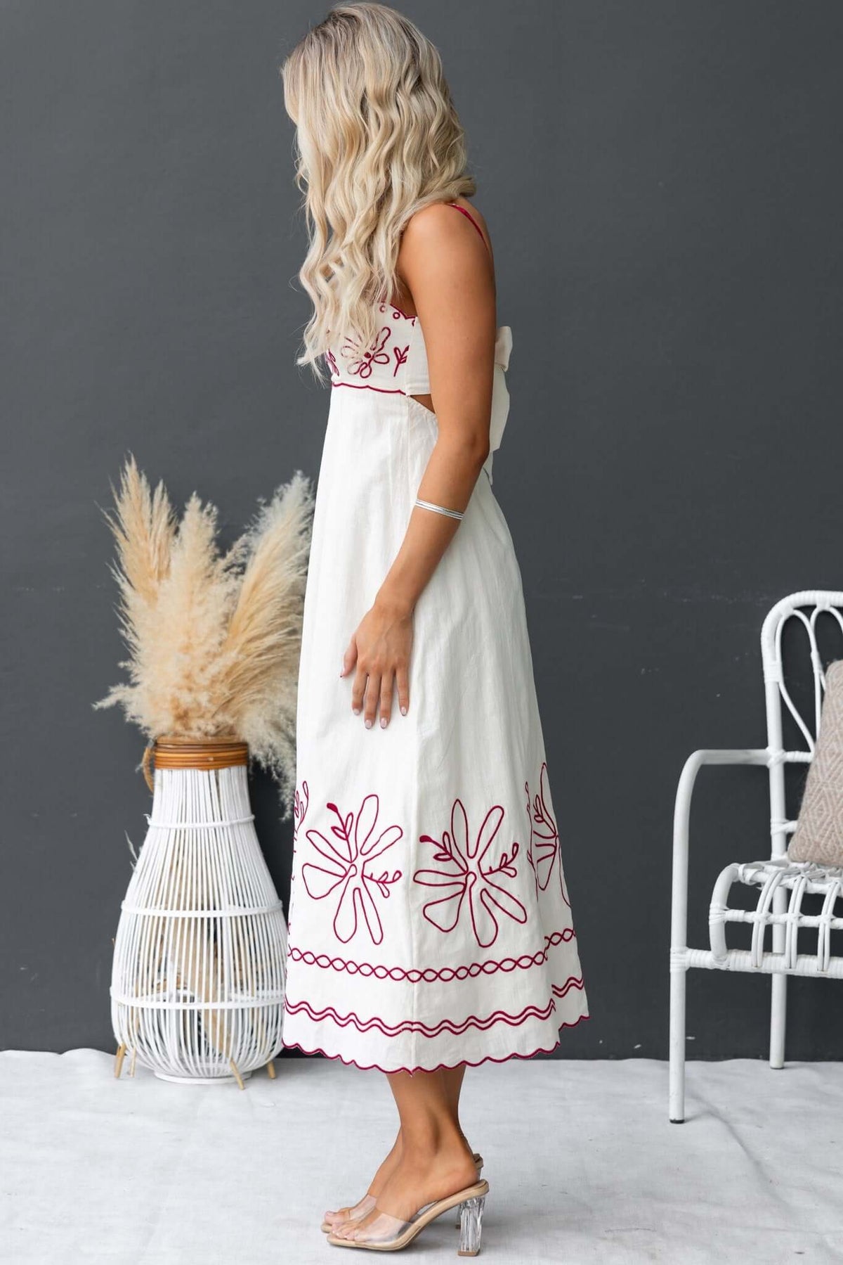 Side view of a woman in a Homestead Midi Dress with floral embroidery, tied back, and adjustable straps.