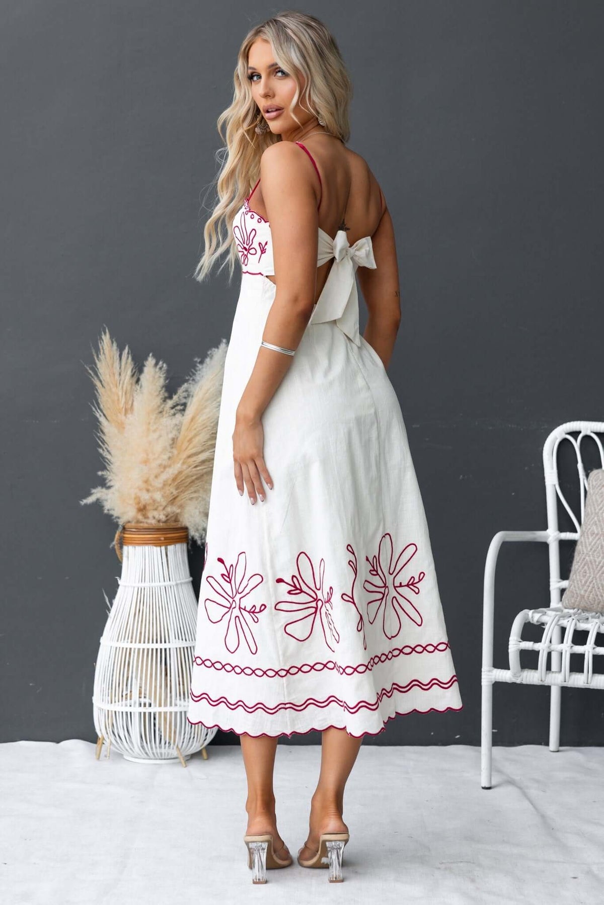 Woman wearing Homestead Midi Dress, showcasing adjustable straps and embroidered details on a white background.