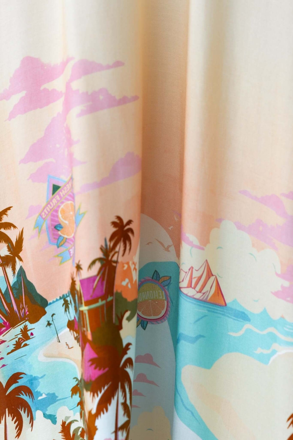 Colorful tropical print with palm trees, sailboats, and clouds on a soft fabric background.