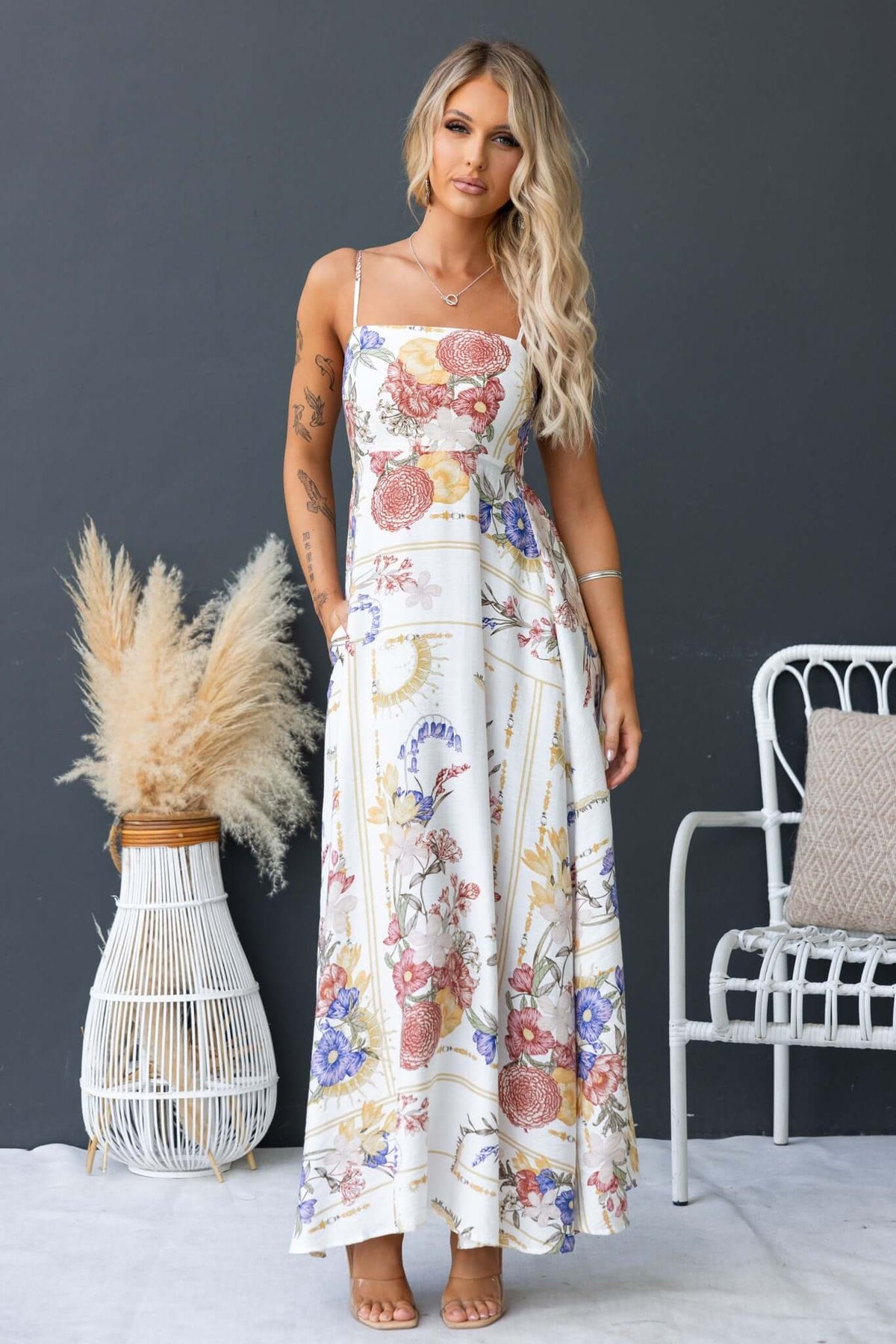 Salilah Maxi Dress with floral print, thin adjustable straps, and pockets, styled on a model in a chic setting.