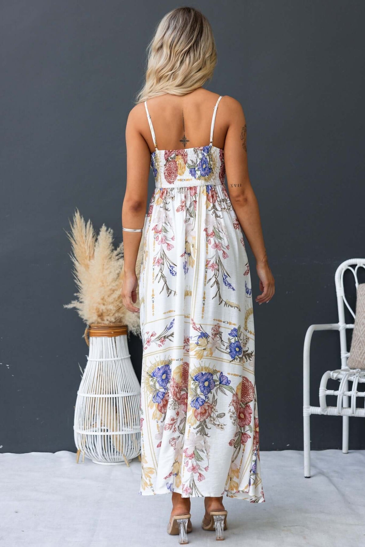 Back view of a model wearing the Salilah Maxi Dress with floral pattern and thin straps, showcasing a flowing design.