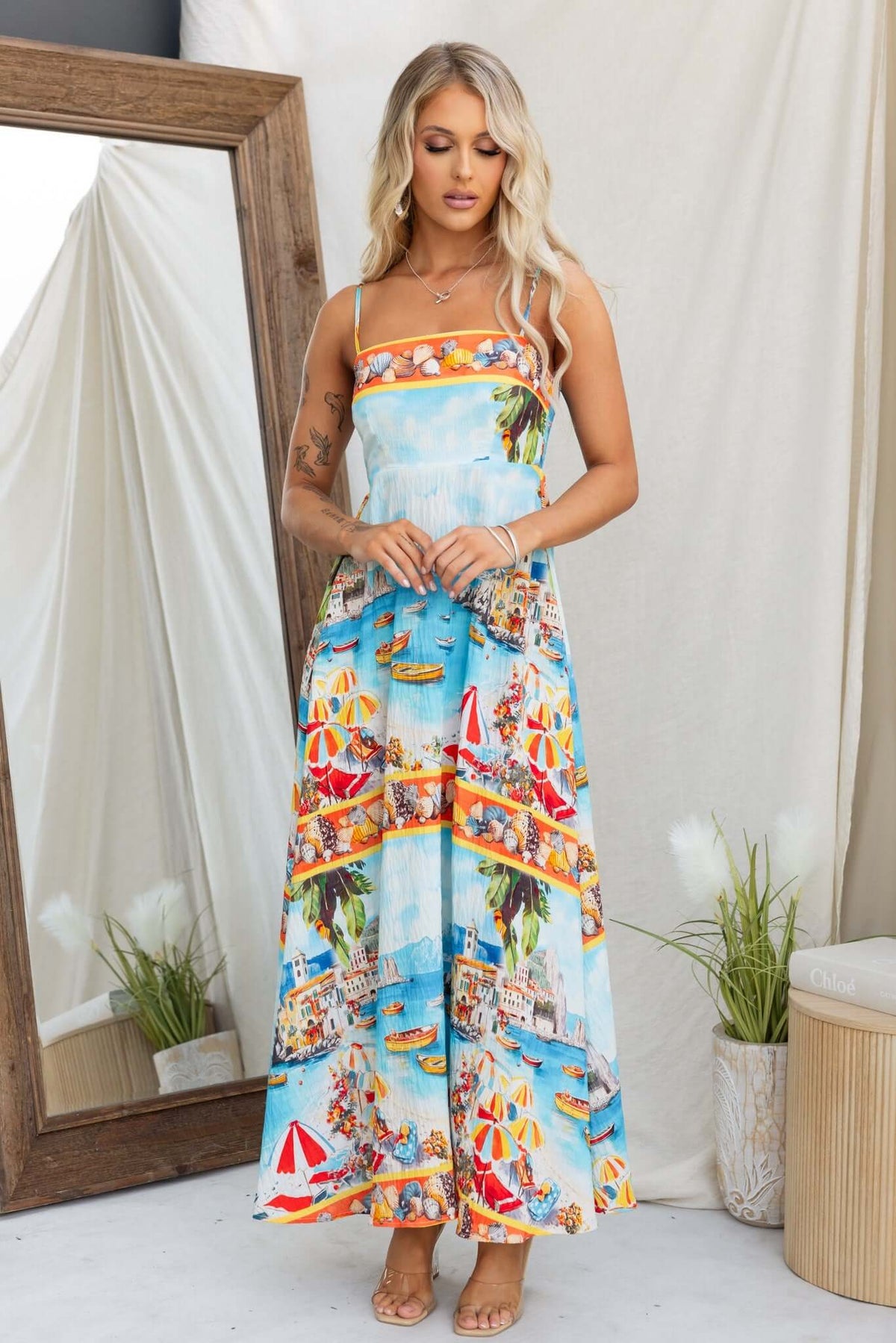 Model wearing Salilah Maxi Dress with vibrant beach print and adjustable straps, showcasing a casual summer style.
