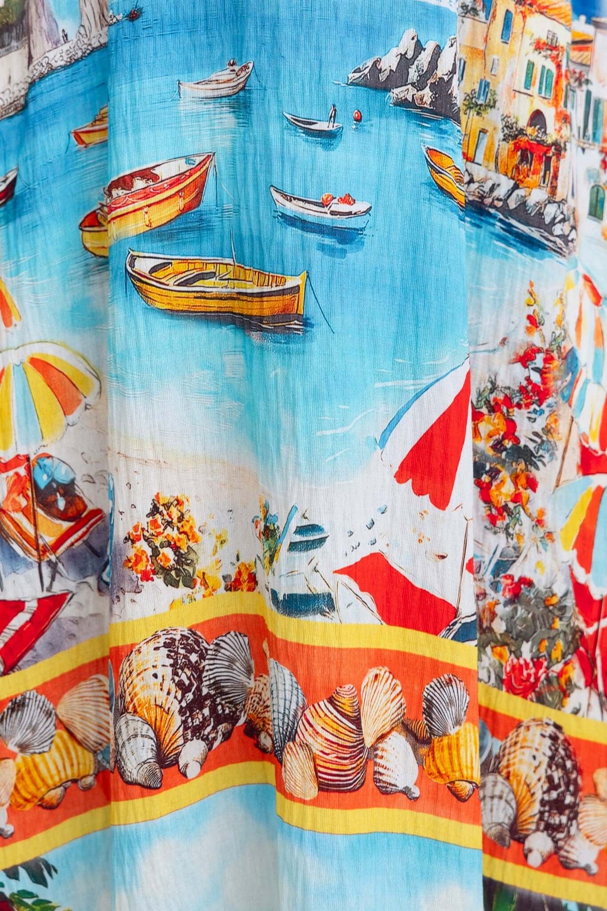Colorful beach scene print featuring boats, umbrellas, and seashells on the Salilah Maxi Dress fabric.