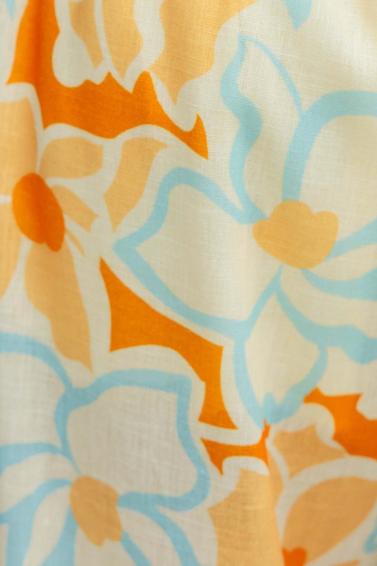 Colorful floral pattern featuring orange and blue flowers on a light background, ideal for summer fashion.