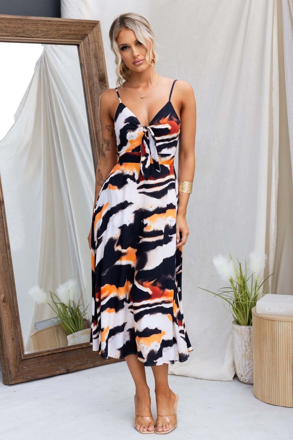 Cecilee Midi Dress featuring adjustable straps, tie at bust, and colorful abstract print, displayed in a chic setting.