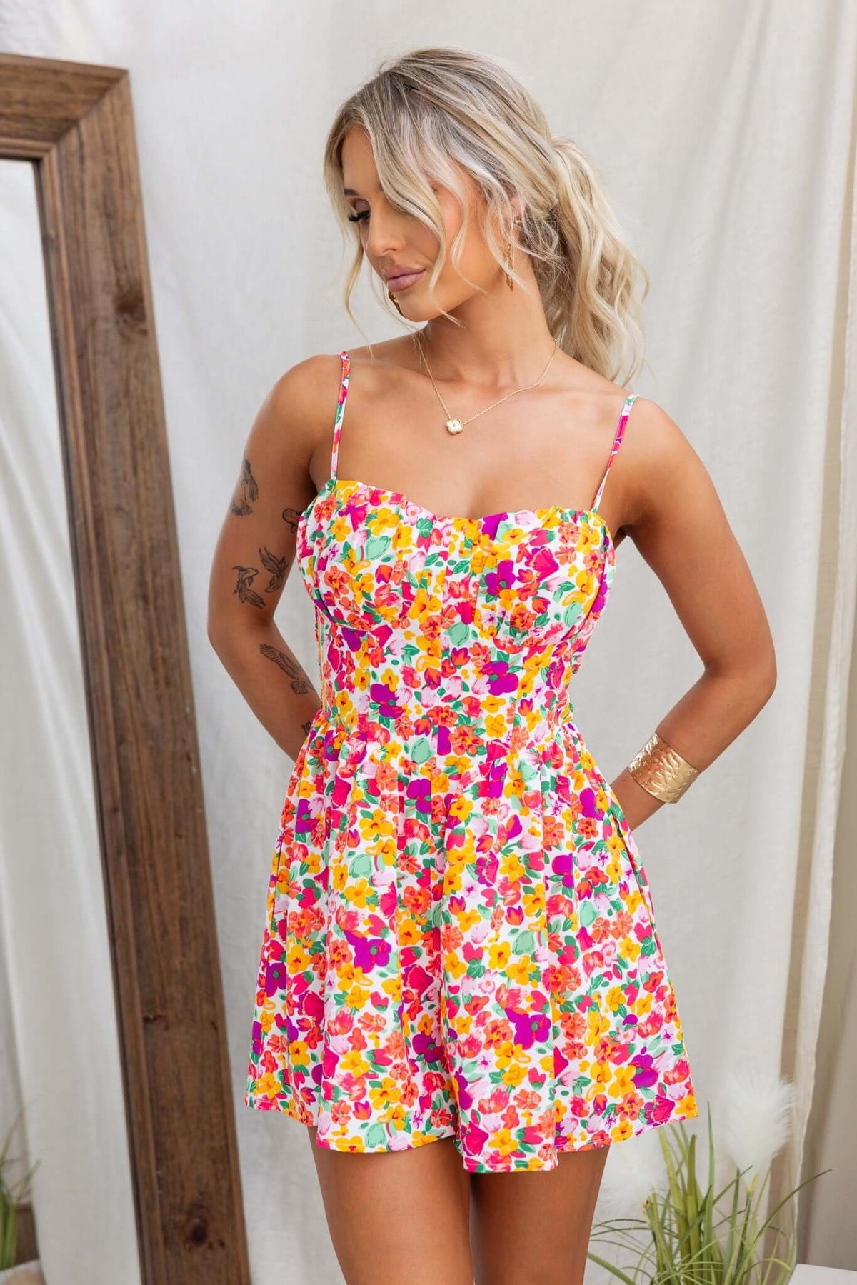 Model wearing the Kaycee Playsuit, featuring a vibrant floral print, adjustable straps, and pockets.