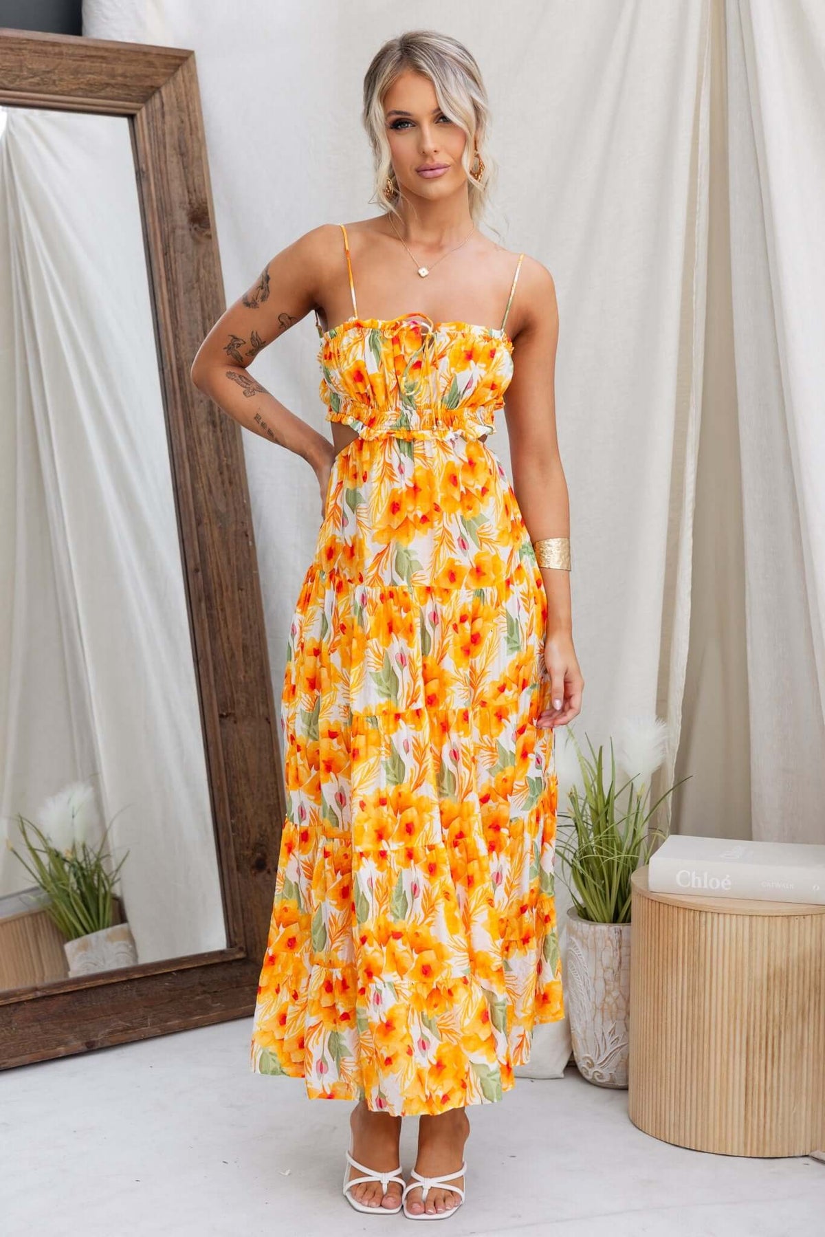 Kohana Maxi Dress in bright yellow floral pattern, featuring adjustable straps and a tied back, styled for summer fashion.