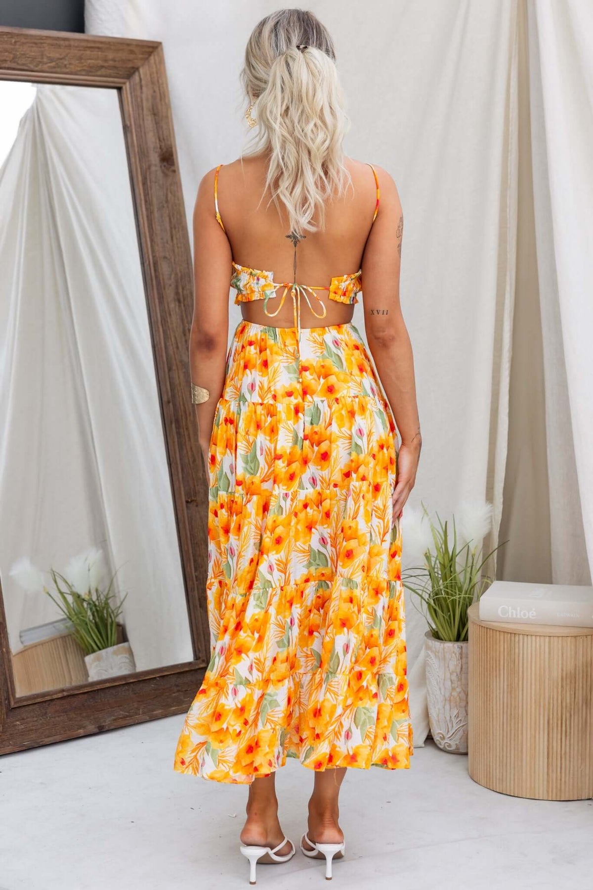 Back view of Kohana Maxi Dress with floral pattern, adjustable straps, and tie detail, model showcases stylish summer wear.