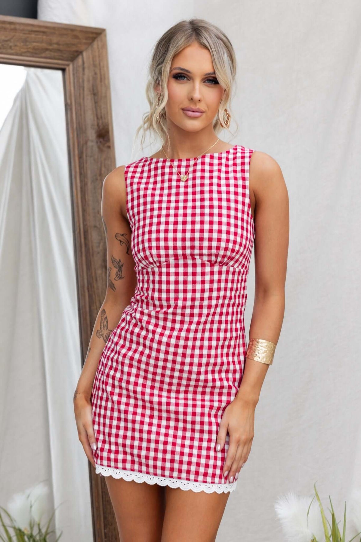 Model wearing the Kairyn Dress, a red and white gingham design with a high neckline and lace trim.