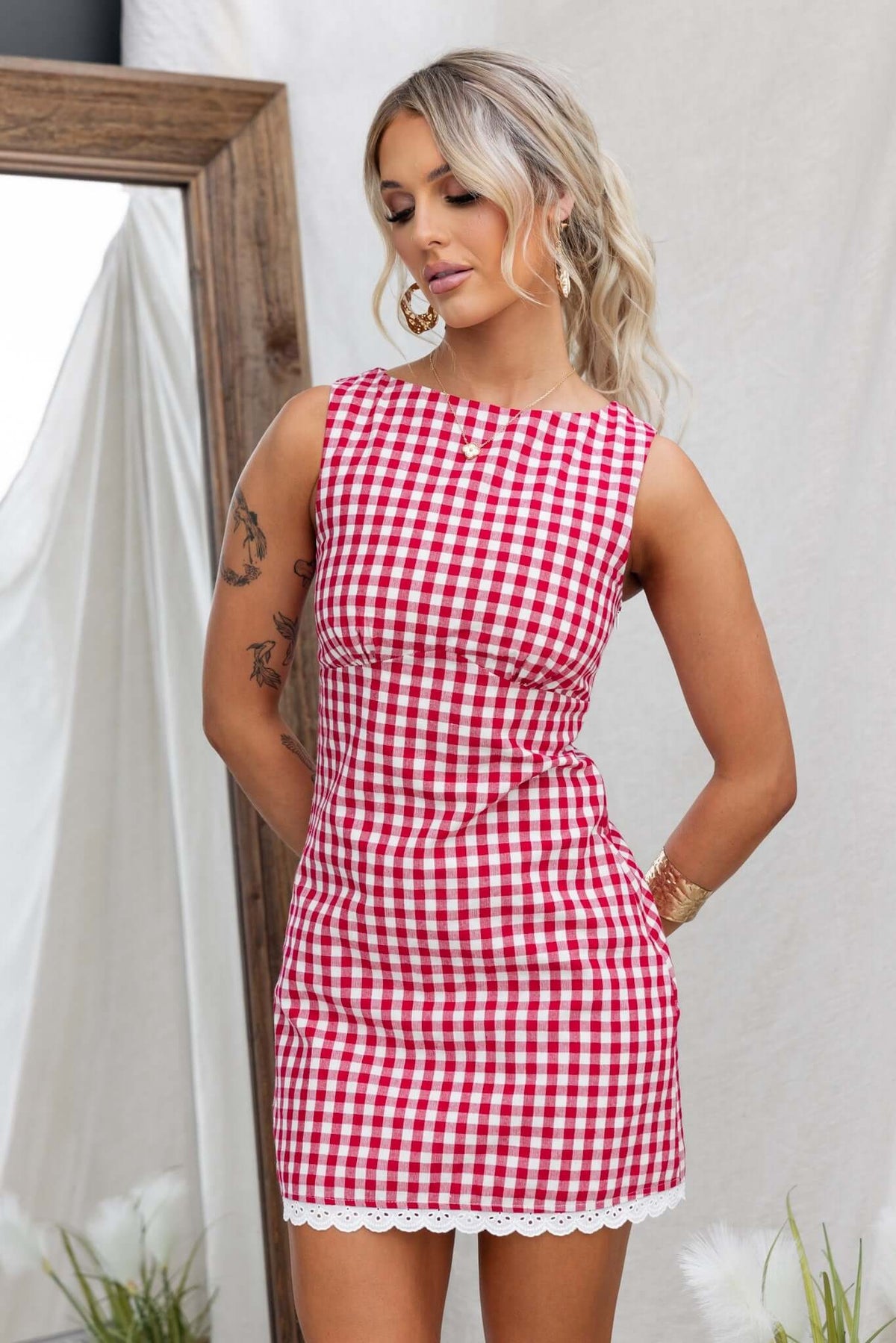 Model wearing Kairyn Dress, a red and white gingham patterned dress with a high neckline and lace trim.