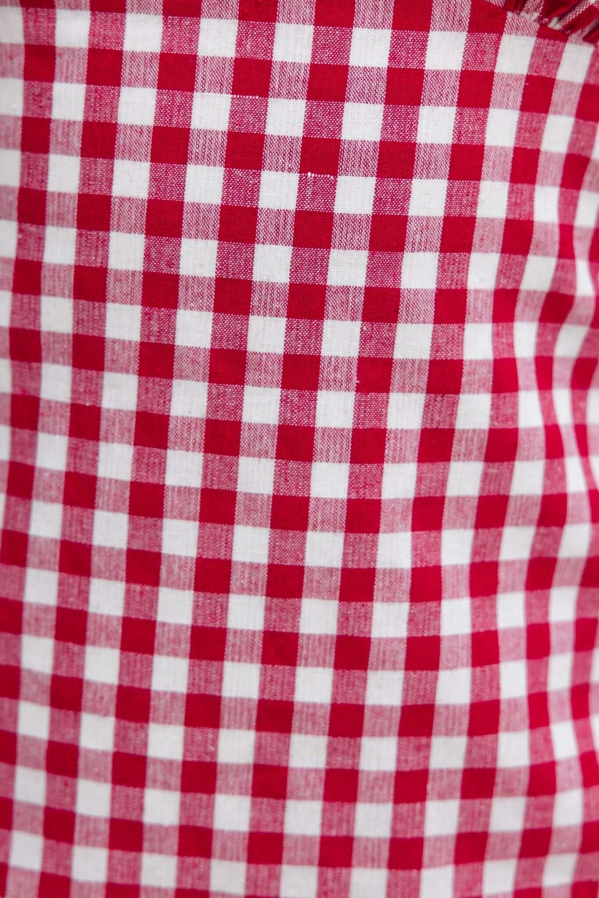 Close-up of red and white gingham fabric, perfect for summer dresses and casual wear.