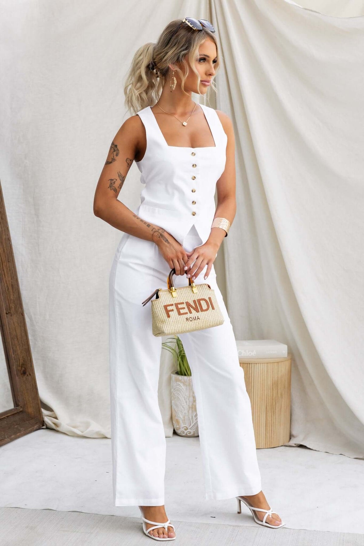 Model wearing Vaylor Pants featuring a mid-high waist and pockets, styled with a white top and a designer handbag.