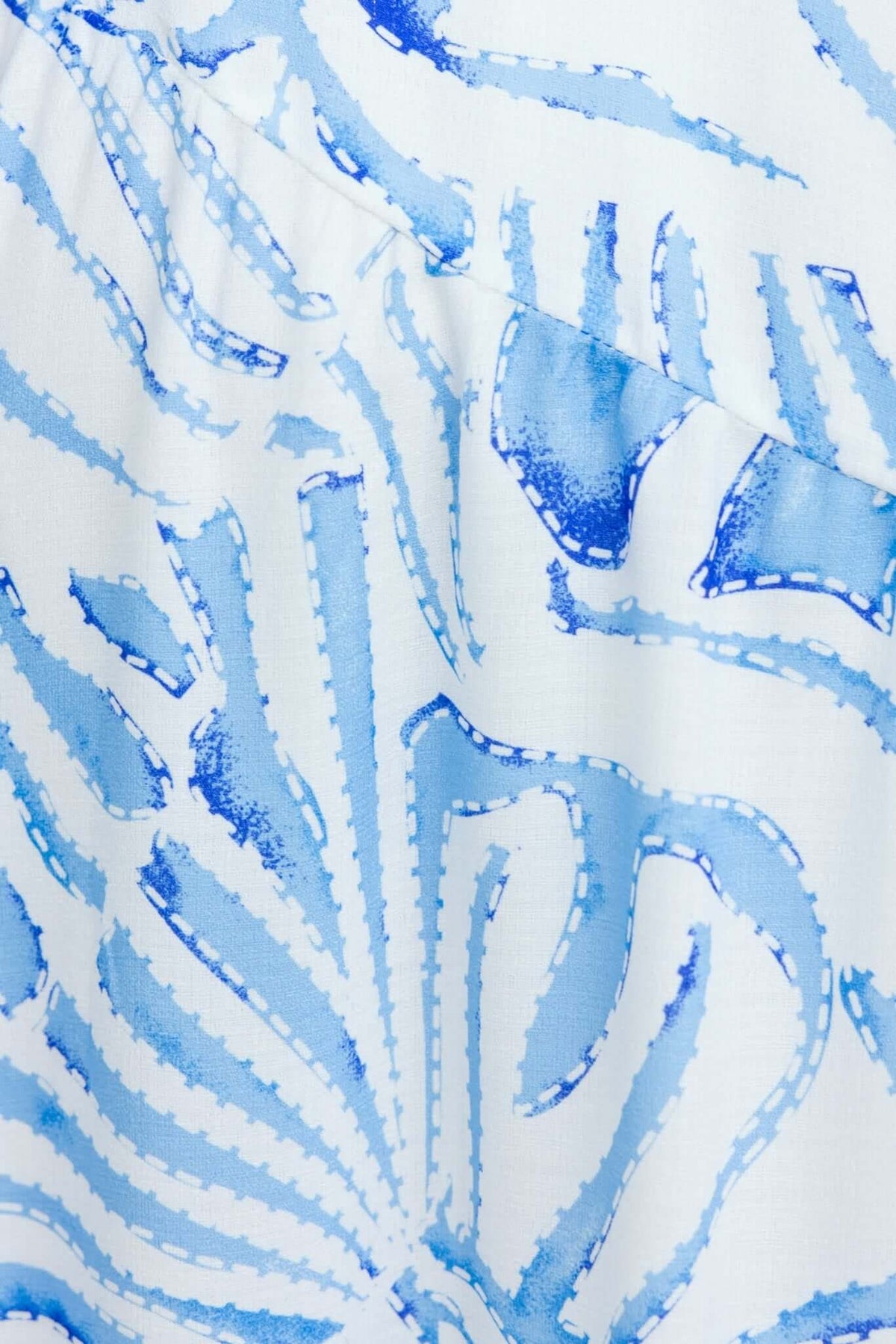 Close-up of blue and white patterned fabric featuring intricate leaf designs, perfect for a summer dress.