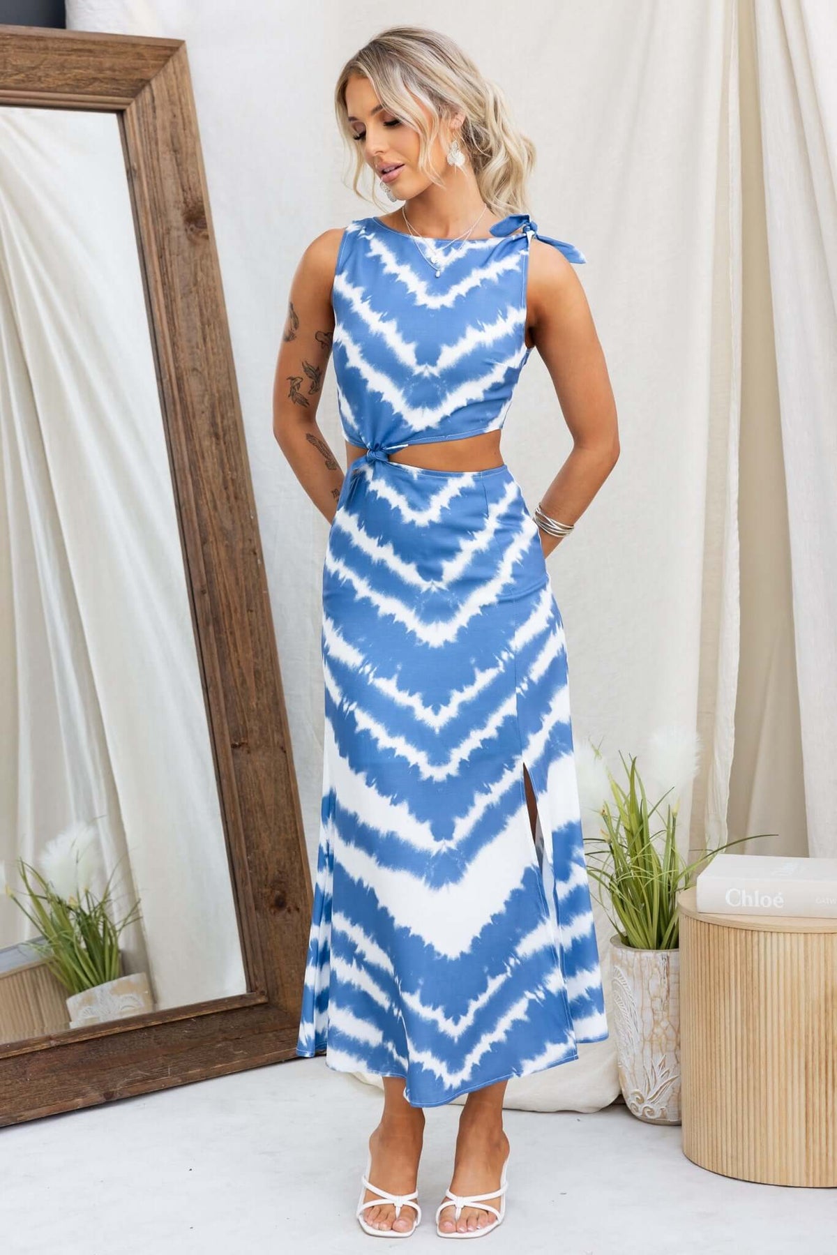 Lauraine Midi Dress in blue tie-dye with shoulder tie and front split, styled in a chic indoor setting.
