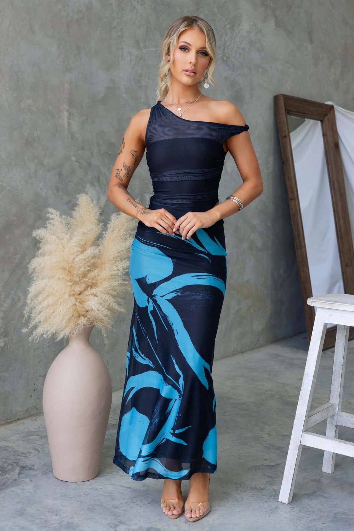 Ovolo Maxi Dress featuring rolled shoulder detail, cut-out side, and vibrant blue floral design.