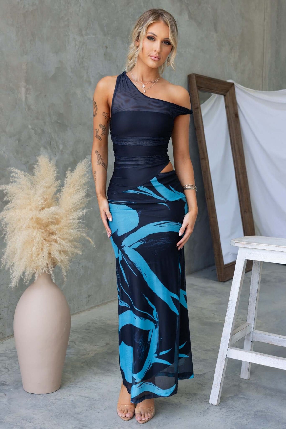 Model wearing Ovolo Maxi Dress featuring rolled shoulder detail and cut out side against a stylish backdrop.