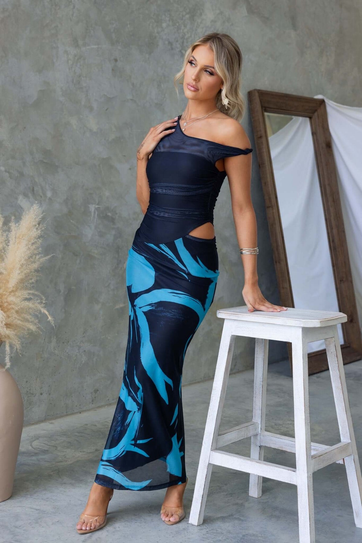 Model wearing the Ovolo Maxi Dress with rolled fabric detail, cut-out sides, and striking blue patterns.