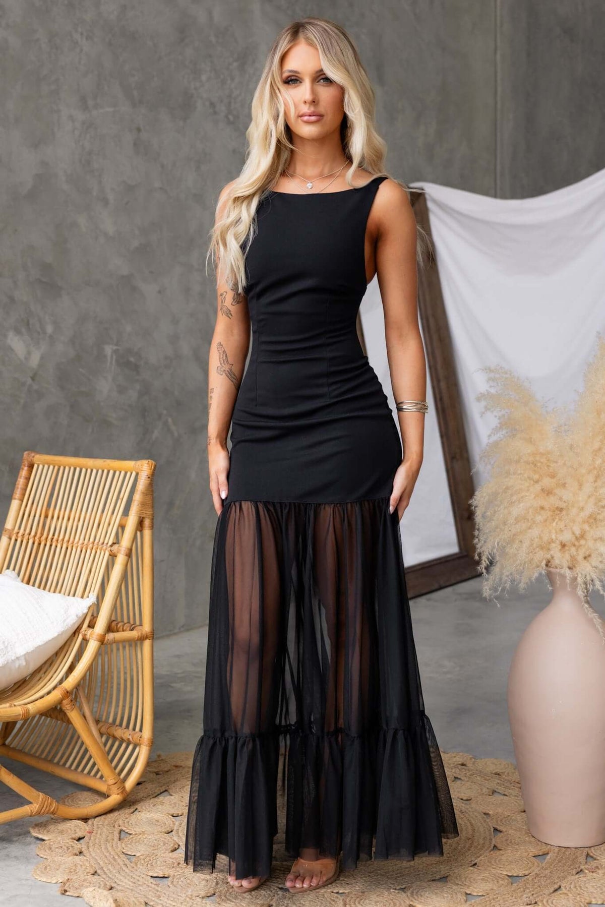 Model wearing a black Nephrite maxi dress with sheer mesh skirt and tie straps, perfect for elegant occasions.