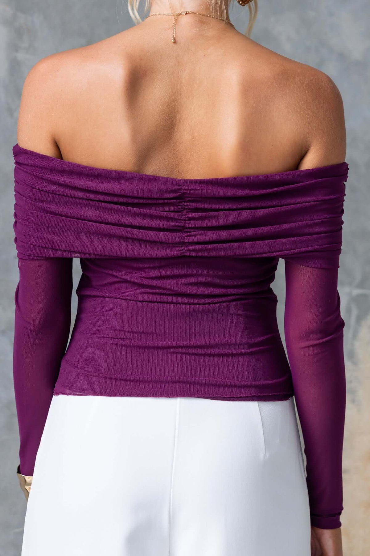 Back view of Arcanna Top featuring an off-shoulder neckline and ruched detail in rich purple color.