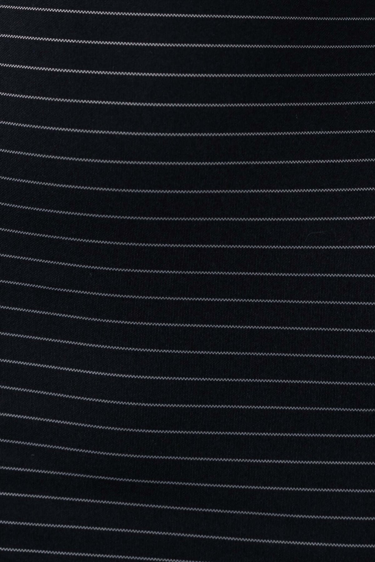 Close-up of black fabric showing thin white stripes, featuring a smooth texture ideal for stylish clothing like dresses.