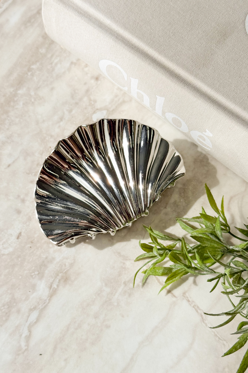 Azure Claw Clip with metallic finish, 10cm length, elegantly styled on marble surface with greenery and a book.