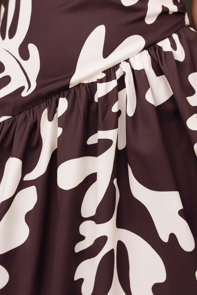 Close-up of the floral print fabric of the Ranier Maxi Dress, featuring a bold brown and white pattern.