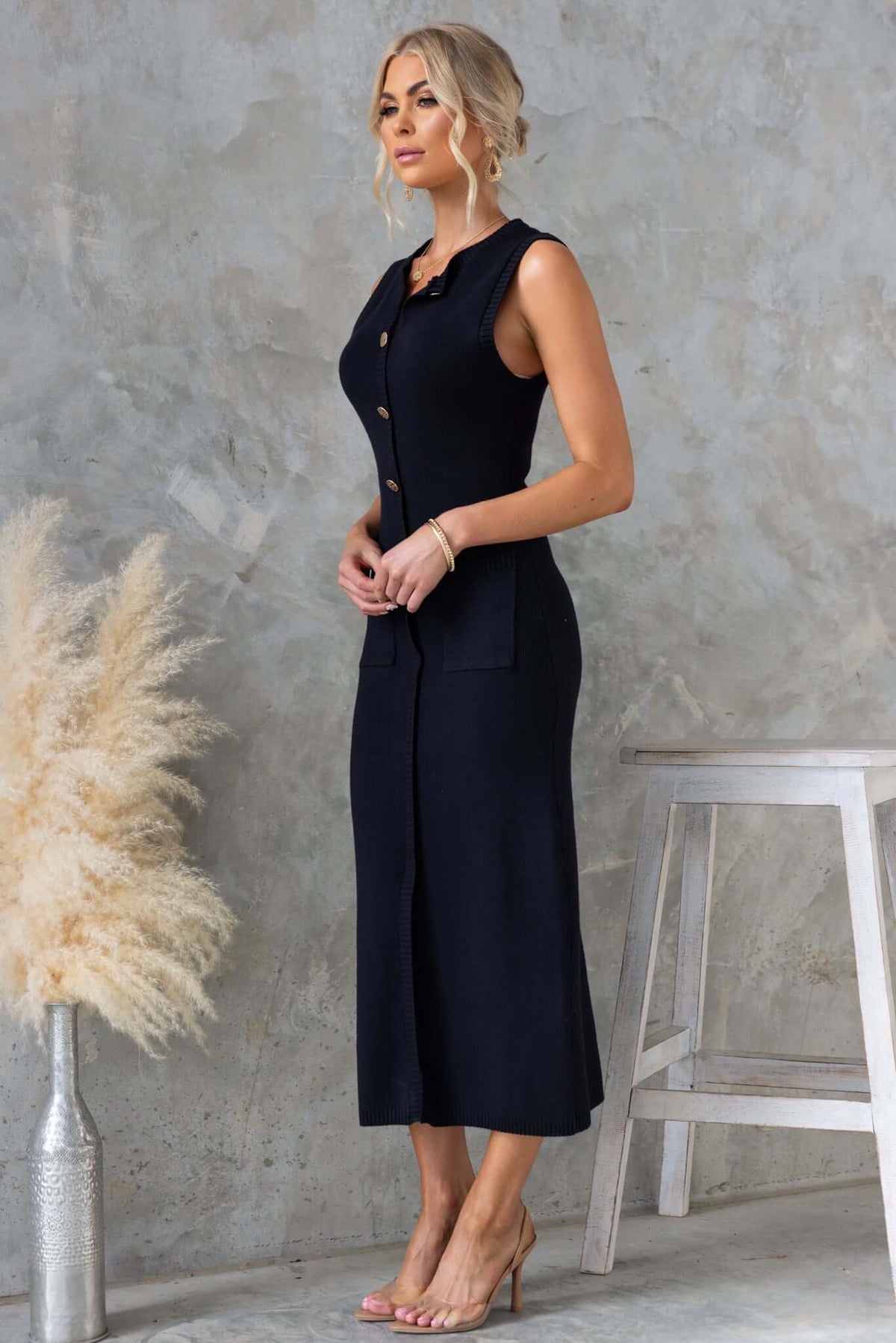 Model wearing a Bari Maxi Dress with high neckline, faux buttons, pockets, and front split in a stylish black color.