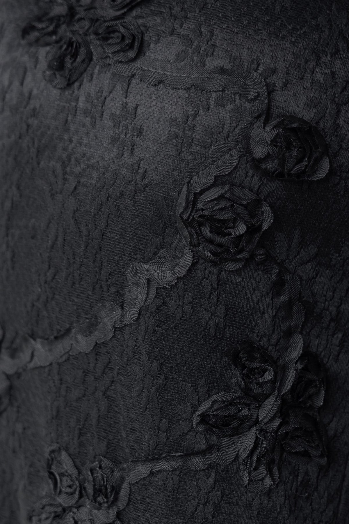 Close-up of textured black fabric featuring delicate floral embroidery, showcasing details of the Metrick Maxi Dress.