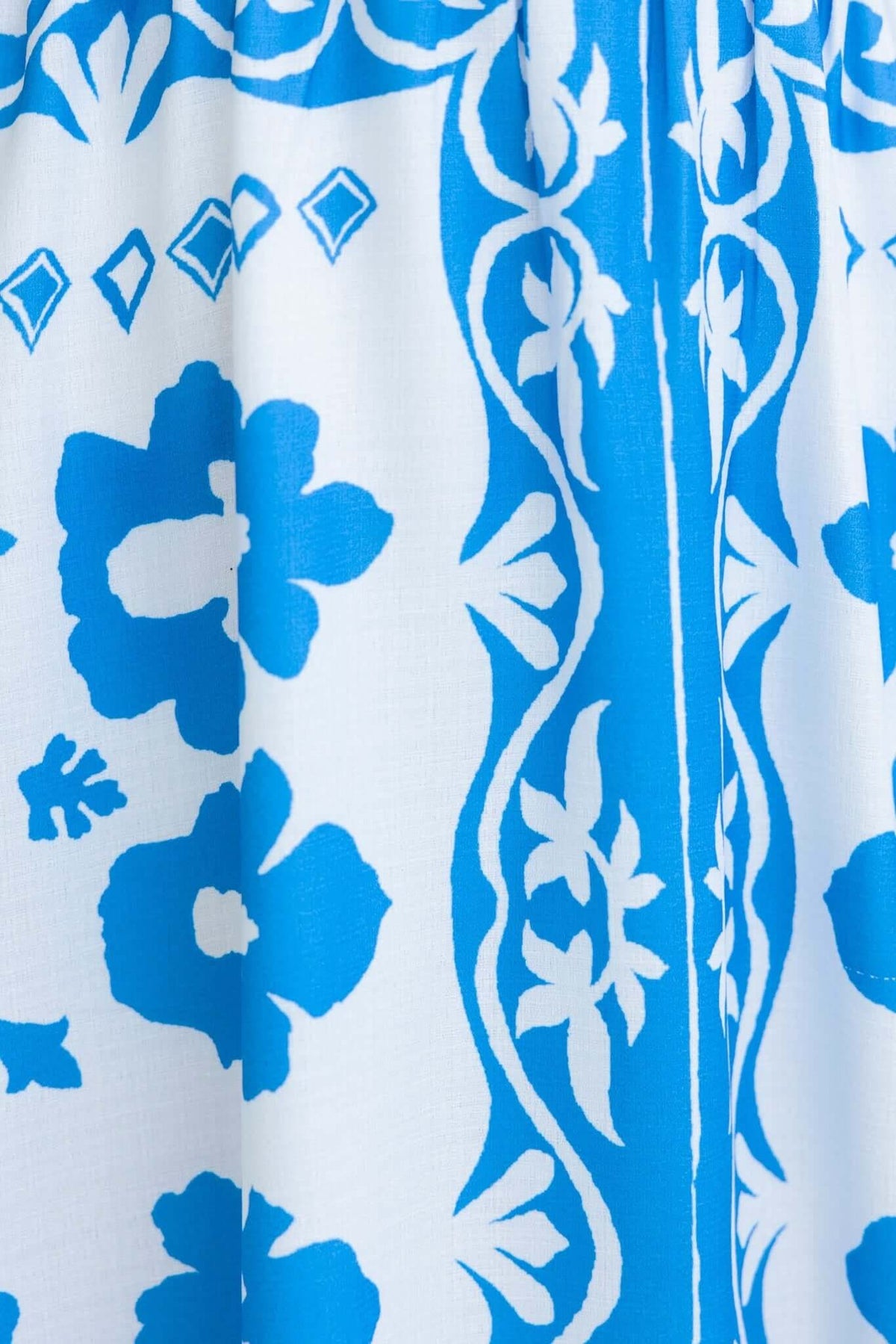 Close-up of Lunya Midi Dress fabric with blue floral and geometric patterns on a white background.