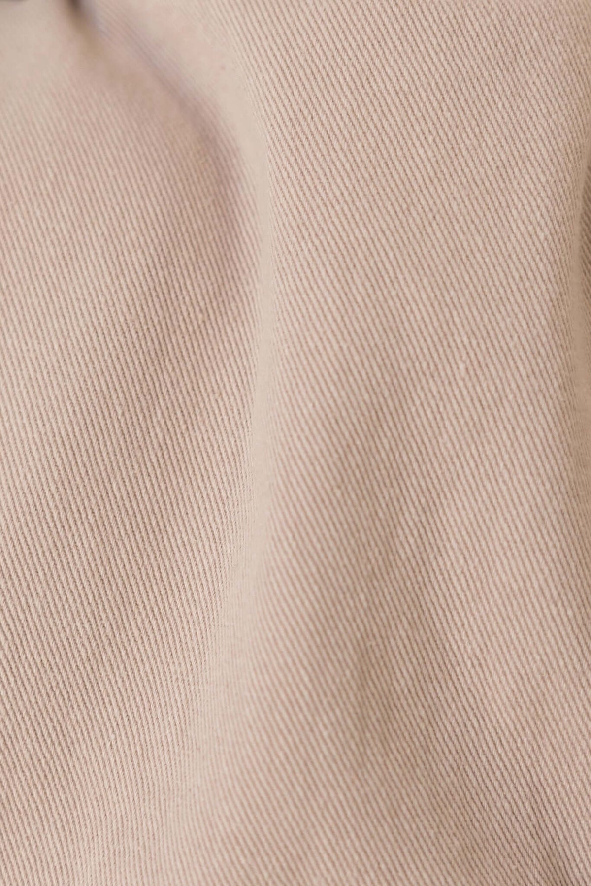 Close-up of the texture of beige denim fabric, showcasing its fine weave and softness.
