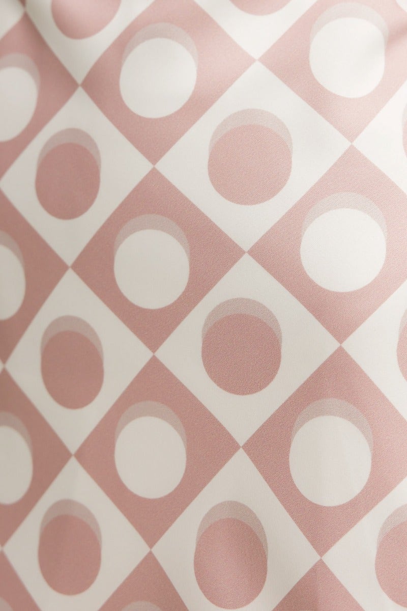 Close-up of pink and white patterned fabric with diamond and circular designs, perfect for a Wishart Maxi Dress.