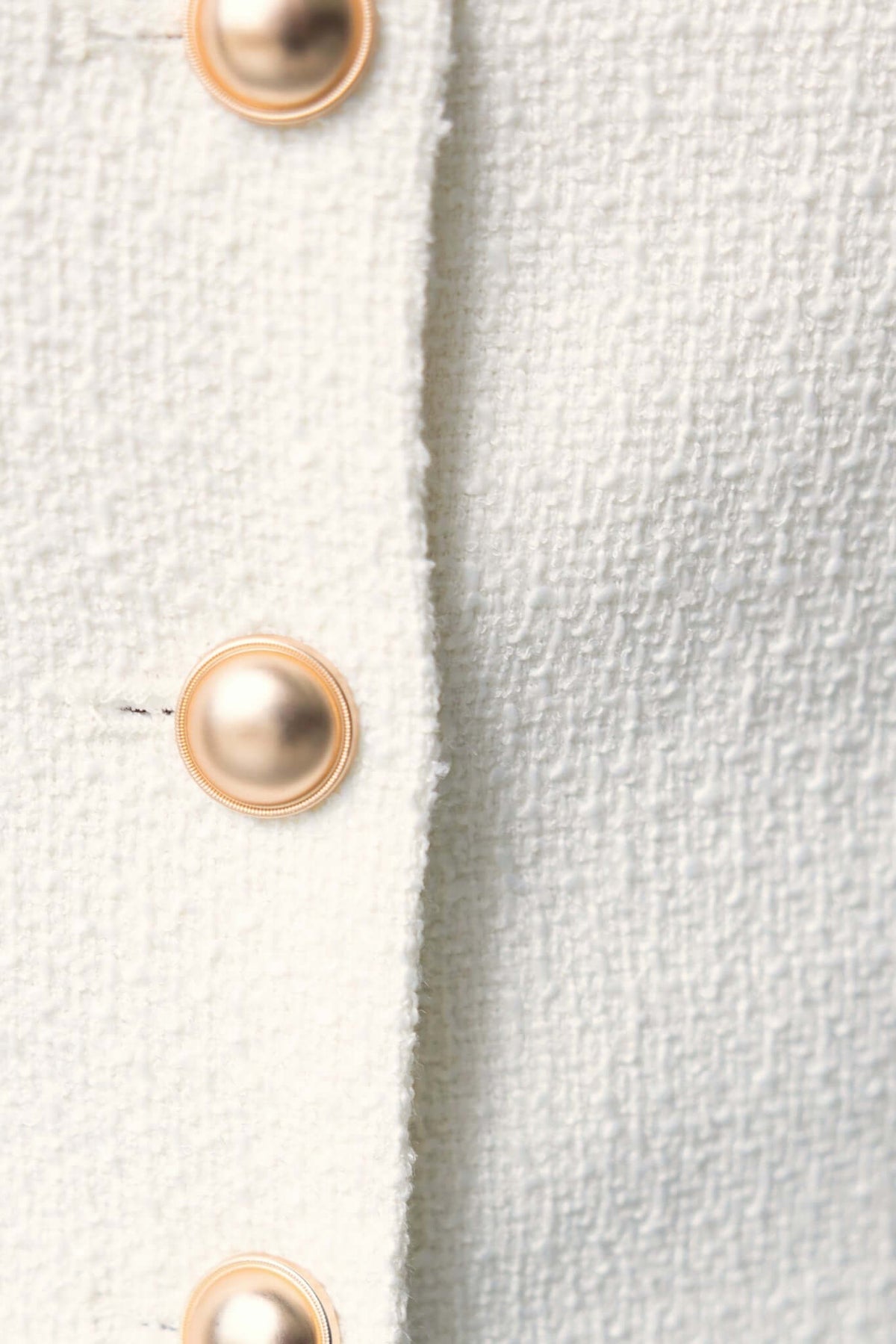 Close-up of button detail on white chenille fabric, showcasing the texture and gold-tone buttons.