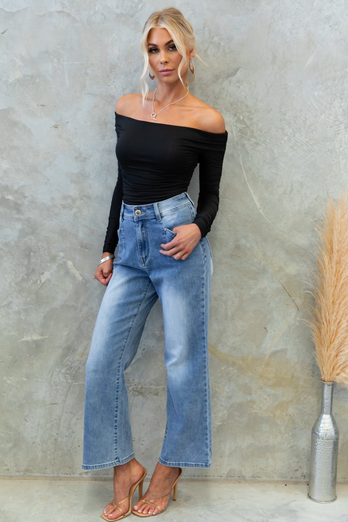 Model wearing Delvey bodysuit in off-shoulder style, paired with high-waisted blue jeans, showcasing casual elegance.