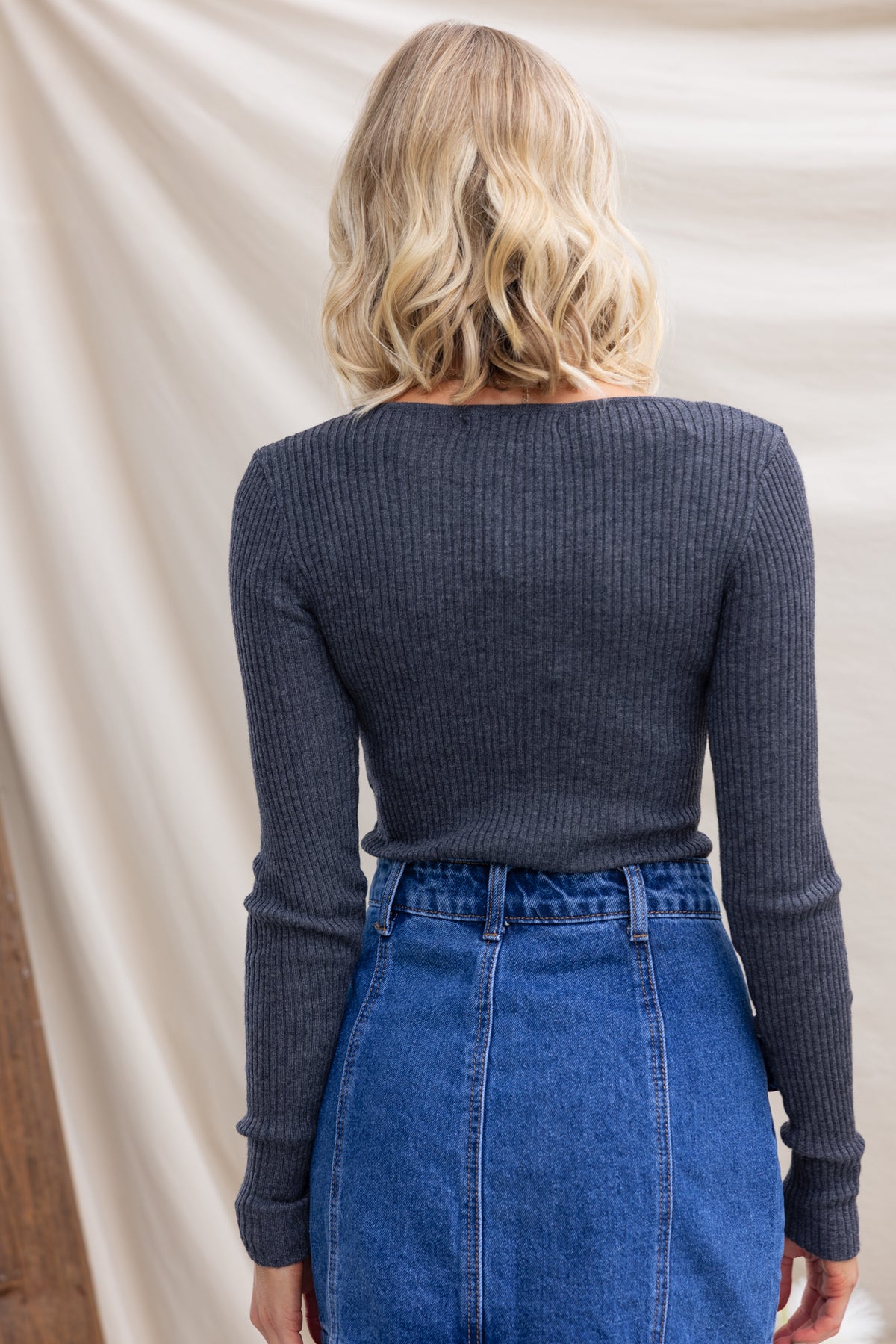 Back view of Draw Me In Top, a ribbed knit top with a round neckline, worn with a high-waisted denim skirt.