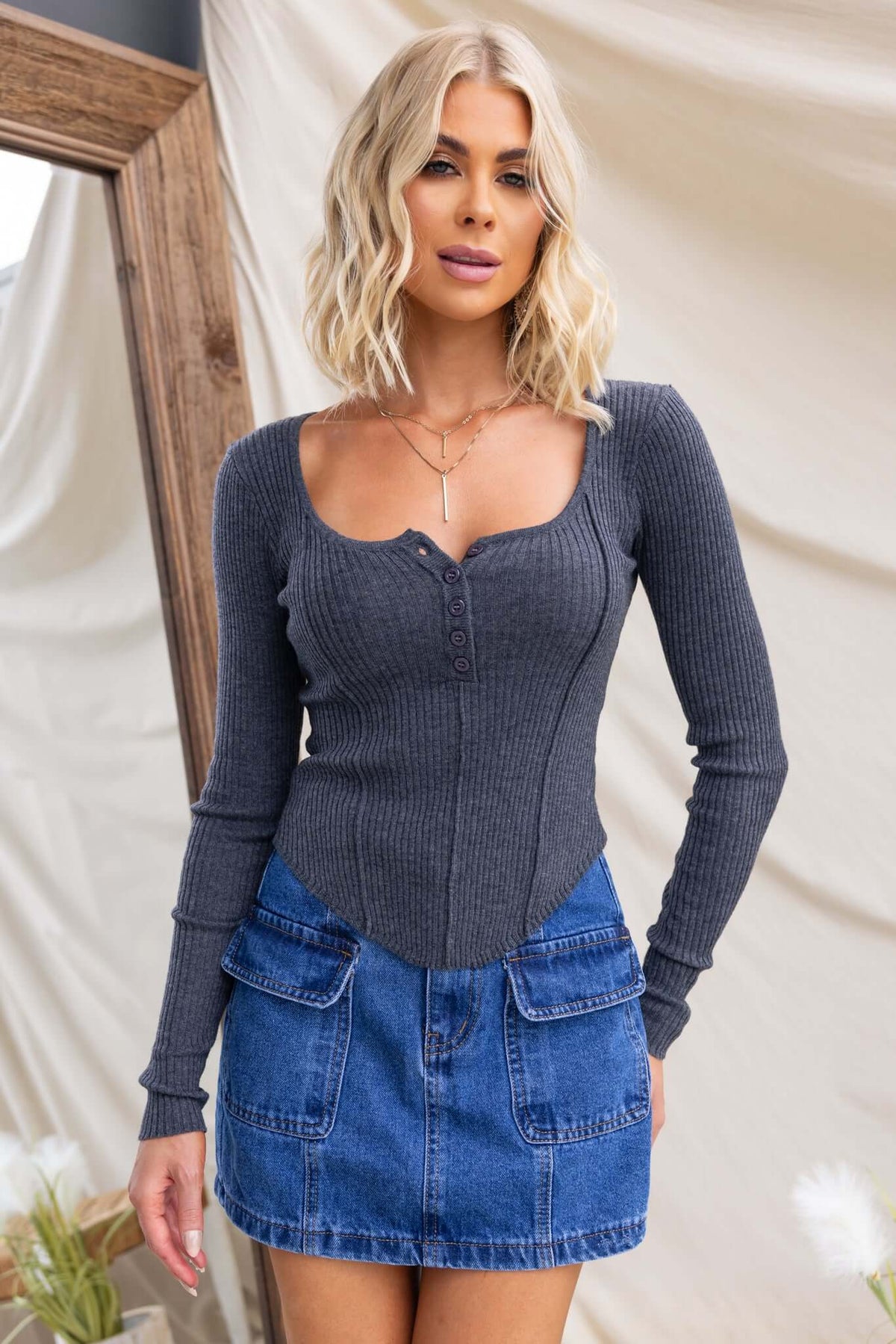 Model wearing the Draw Me In Top featuring a round neckline, button-up bust, and tapered hem with a denim skirt.
