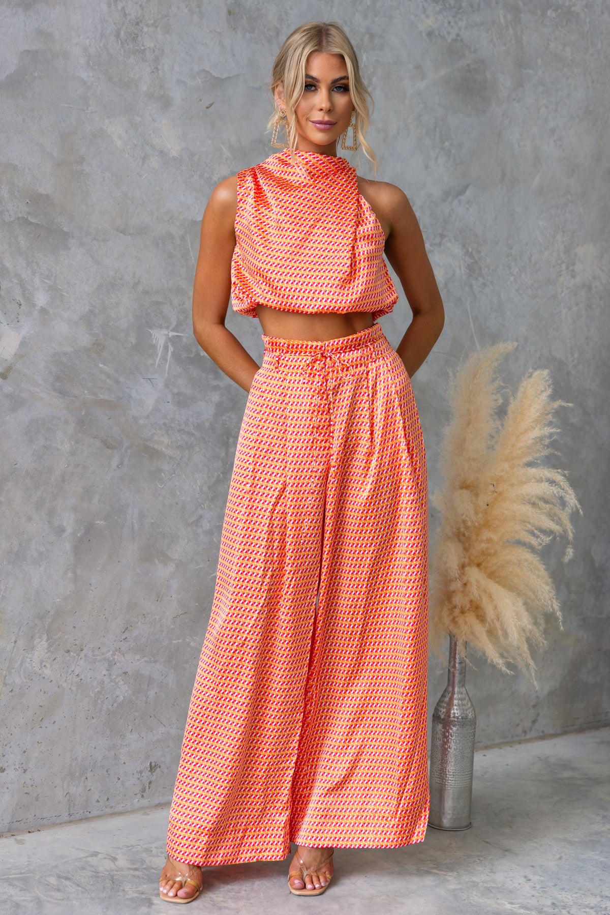 Model wearing Dreamie Set featuring a high-neck crop top and wide-leg pants in vibrant orange pattern.