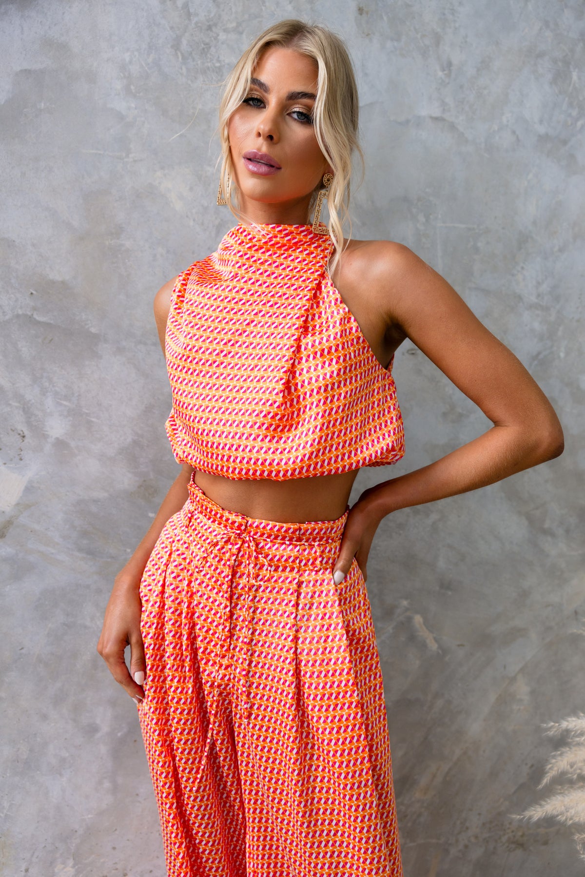 Model showcasing the Dreamie Set: a satin-like cropped top and mid-high waist pants in a vibrant orange pattern.
